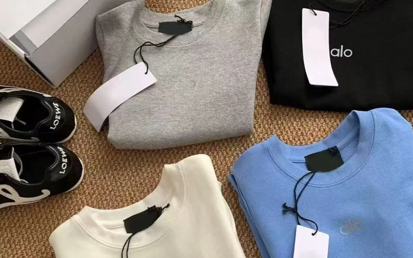 Coordinated casual clothing and trainers arranged on a neutral woven background