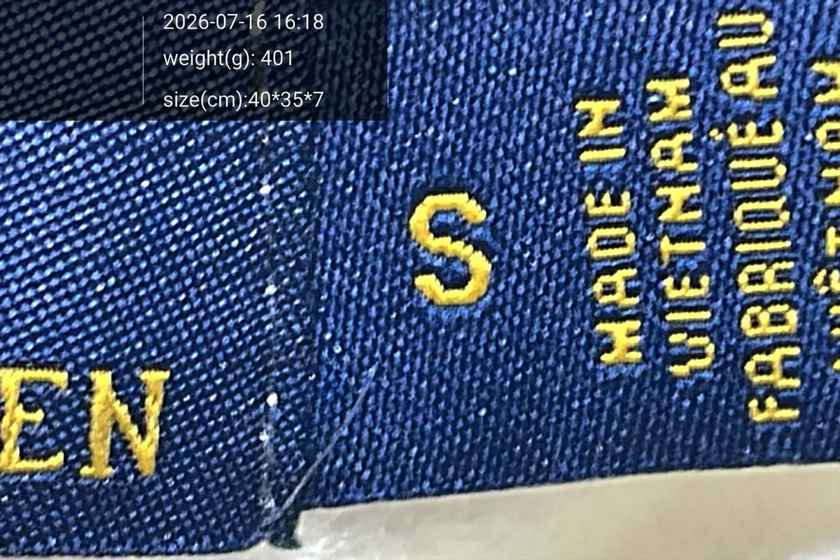 Close-up warehouse QC photograph of the neck label and knit construction